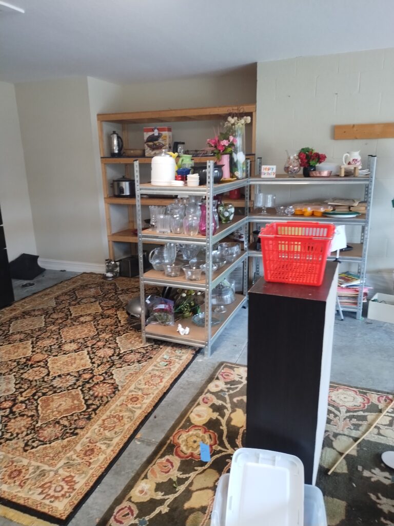 Garage sale leftovers including storage items rugs and glassware awaiting removal in Crystal River Florida